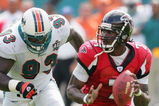 MIAMI - NOVEMBER 6:  Quarterback Michael Vick #7 of the Atlanta Falcons looks for a receiver as he avoids a tackle by defensive end Kevin Carter #93 of the Miami Dolphins on November 6, 2005 at Dolphins Stadium in Miami, Florida. The Falcons defeated the Dolphins 17-10. (Photo by Paul Spinelli/Getty Images)