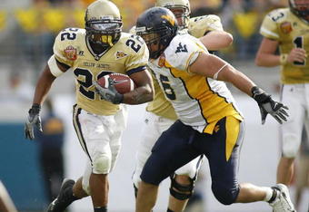 JACKSONVILLE, FL - JANUARY 01:  Running back Tashard Choice #22 of the Georgia Tech Yellow Jackets runs through nose tackle Keilen Dykes #96  of the West Virginia Mountaineers defense in the Toyota Gator Bowl at Alltel Stadium January 1, 2007 in Jacksonville, Florida.  (Photo by Marc Serota/Getty Images)