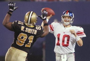 EAST RUTHERFORD, NJ - SEPTEMBER 19:  Quarterback Eli Manning #10 of the New York Giants throws a pass over the defense of Will Smith #91 of the New Orleans Saints in the second quarter September 19, 2005 at Giants Stadium in East Rutherford, New Jersey. The Saints are playing their home opener, with proceeds going to the Hurricane Katrina relief fund, in New Jersey after being forced from the Superdome which was damaged by Hurricane Katrina.  (Photo by Jim McIsaac/Getty Images)
