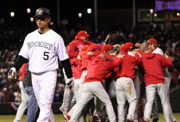 DENVER - OCTOBER 12:  The Philadelphia Phillies celebrate their 5-4 win as Carlos GOnzalez #5 of the Colorado Rockies walks off the field dejected after Game Four of the NLDS during the 2009 MLB Playoffs at Coors Field on October 12, 2009 in Denver, Colorado. (Photo by Jed Jacobsohn/Getty Images)