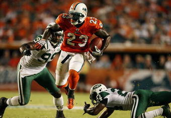 MIAMI - OCTOBER 12:  Running back Ronnie Brown #23 of the Miami Dolphins jumps between linebacker Bryan Thomas #99 and cornerback Darrelle Revis #24 of the New York Jets at Land Shark Stadium on October 12, 2009 in Miami, Florida. The Dolphins defeated the Jets 31-27.  (Photo by Doug Benc/Getty Images)