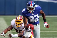 EAST RUTHERFORD, NJ - SEPTEMBER 13:  Mario Manningham #82 of the New York Giants eludes a tackle attempt from Andre Carter #99 of the Washington Redskins enroute to a touchdown on September 13, 2009 at Giants Stadium in East Rutherford, New Jersey.  (Photo by Jim McIsaac/Getty Images)