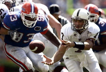 GAINESVILLE, FL - OCTOBER 8:  Quarterback Michael Henig #7 of Mississippi State hands off with defensive linemen Steven Harris #93 of the University of Florida in pursuit on October 8, 2005 at Ben Hill Griffin Stadium in Gainesville, Florida.  (Photo by Eliot J. Schechter/Getty Images)