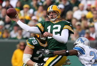 GREEN BAY, WI - OCTOBER 18: Aaron Rodgers #12 of the Green Bay Packers leaps to throw a pass under pressure from Kevin Hobbs #23 of the Detroit Lions at Lambeau Field on October 18, 2009 in Green Bay, Wisconsin. The Packers defeated the Lions 26-0.  (Photo by Jonathan Daniel/Getty Images)