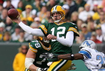 GREEN BAY, WI - OCTOBER 18: Aaron Rodgers #12 of the Green Bay Packers leaps to throw a pass under pressure from Kevin Hobbs #23 of the Detroit Lions at Lambeau Field on October 18, 2009 in Green Bay, Wisconsin. The Packers defeated the Lions 26-0.  (Photo by Jonathan Daniel/Getty Images)