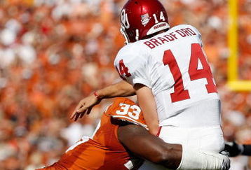 DALLAS - OCTOBER 17:  Quarterback Sam Bradford #14 of the Oklahoma Sooners is tackled by Lamarr Houston #33 of the Texas Longhorns at Cotton Bowl on October 17, 2009 in Dallas, Texas.  (Photo by Ronald Martinez/Getty Images)