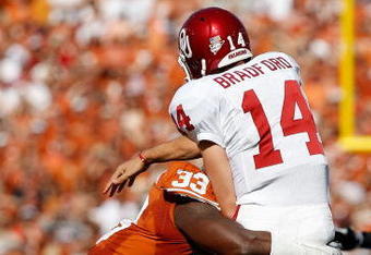 DALLAS - OCTOBER 17:  Quarterback Sam Bradford #14 of the Oklahoma Sooners is tackled by Lamarr Houston #33 of the Texas Longhorns at Cotton Bowl on October 17, 2009 in Dallas, Texas.  (Photo by Ronald Martinez/Getty Images)