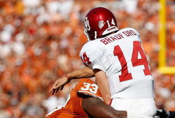 DALLAS - OCTOBER 17:  Quarterback Sam Bradford #14 of the Oklahoma Sooners is tackled by Lamarr Houston #33 of the Texas Longhorns at Cotton Bowl on October 17, 2009 in Dallas, Texas.  (Photo by Ronald Martinez/Getty Images)