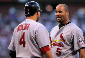 DENVER - SEPTEMBER 26:  Albert Pujols #5 of the St. Louis Cardinals is welcomed home by Yadier Molina #4 after Pujols scored in the first inning against the Colorado Rockies at Coors Field on September 26, 2009 in Denver, Colorado. The Cardinals clinched the National League Central Division when they defeated the Rockies 6-3.  (Photo by Doug Pensinger/Getty Images)