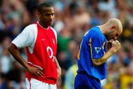 LONDON - MAY 4:  Thierry Henry of Arsenal looks dejected after they lose the match and championship as Danny Mills of Leeds United celebrates a vital win to keep them from slipping into relegation trouble after the FA Barclaycard Premiership match held on May 4, 2003 at Highbury, in London. Leeds United won the match 3-2. (Photo by Ben Radford/Getty Images)