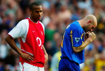 LONDON - MAY 4:  Thierry Henry of Arsenal looks dejected after they lose the match and championship as Danny Mills of Leeds United celebrates a vital win to keep them from slipping into relegation trouble after the FA Barclaycard Premiership match held on May 4, 2003 at Highbury, in London. Leeds United won the match 3-2. (Photo by Ben Radford/Getty Images)