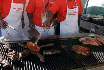 FONTANA, CA - SEPTEMBER 3:  (L-R) Basketball player Grant Hill helps out Kairi Brown and his father Larry Brown at a BBQ during the NASCAR Nextel Cup Series Sony HD 500 on September 3, 2005 in Fontana, California.  (Photo by Robert Laberge/Getty Images)