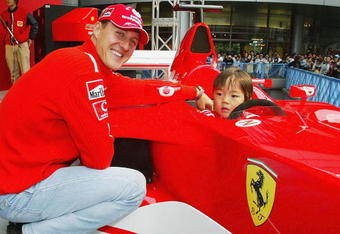 TOKYO - OCTOBER 8:  Michael Schumacher of Germany and Ferrari poses with a local child during an appearance at the Showa Shell headquarters on October 8, 2003 in Tokyo, Japan. (Photo by Clive Mason/Getty Images).