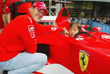 TOKYO - OCTOBER 8:  Michael Schumacher of Germany and Ferrari poses with a local child during an appearance at the Showa Shell headquarters on October 8, 2003 in Tokyo, Japan. (Photo by Clive Mason/Getty Images).