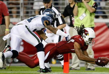GLENDALE, AZ - NOVEMBER 15:  Larry Fitzgerald #11 of the Arizona Cardinals dives across the goal line for a touchdown while being pursued by Ken Lucas #31 of the Seattle Seahawks in the second half at University of Phoenix Stadium on November 15, 2009 in Glendale, Arizona. The Cardinals defeated the Seahawks 31-20.  (Photo by Jeff Gross/Getty Images)