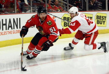 CHICAGO - MAY 22:  Brian Campbell #51 of the Chicago Blackhawks skates with the puck against Darren Helm #43 of the Detroit Red Wings during Game Three of the Western Conference Championship Round of the 2009 Stanley Cup Playoffs on May 22, 2009 at the United Center in Chicago, Illinois. The Blackhawks won 4-3 in overtime. (Photo by Jonathan Daniel/Getty Images)