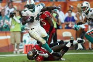 MIAMI GARDENS, FL - NOVEMBER 15:  Running back Ricky Williams #34 of the Miami Dolphins is brought down by linebacker Geno Hayes #54 of the Tampa Bay Buccaneers to finish off a 27-yard run to set up a game-winning field goal by Dan Carpenter #5  to beat the Buccaneers at Land Shark Stadium on November 15, 2009 in Miami Gardens, Florida. The Dolphins defeated the Buccaneers 25-23.  (Photo by Doug Benc/Getty Images)