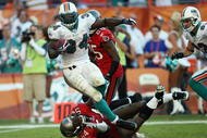 MIAMI GARDENS, FL - NOVEMBER 15:  Running back Ricky Williams #34 of the Miami Dolphins is brought down by linebacker Geno Hayes #54 of the Tampa Bay Buccaneers to finish off a 27-yard run to set up a game-winning field goal by Dan Carpenter #5  to beat the Buccaneers at Land Shark Stadium on November 15, 2009 in Miami Gardens, Florida. The Dolphins defeated the Buccaneers 25-23.  (Photo by Doug Benc/Getty Images)