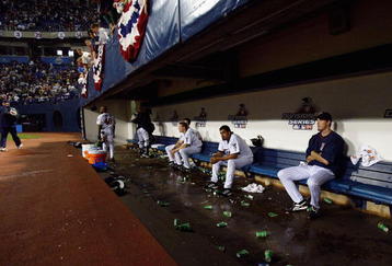 MINNEAPOLIS - OCTOBER 9:  Some Minnesota Twins players sit on the bench and watch s the New York Yankees celebrate on the field after defeating the Twins during game four of the American League Divisional Series at the Hubert H. Humphrey Metrodome on October 9, 2004 in Minneapolis, Minnesota.The Yankees defeated the Twins 6-5 to advance to the American League Championship Series against the Boston Red Sox. (Photo by Jed Jacobsohn/Getty Images)