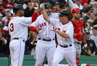 BOSTON - OCTOBER 11:  (2nd R) J.D. Drew #7 of the Boston Red Sox celebrates with teammates (L) Alex Gonzalez #3 and Mike Lowell #25 as (R) Mike Napoli #44 of the Los Angeles Angels of Anaheim looks on after Drew's two-run home run in the fourth inning of Game Three of the ALDS during the 2009 MLB Playoffs at Fenway Park on October 11, 2009 in Boston,  Massachusetts. (Photo by Jim Rogash/Getty Images)