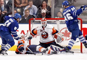 TORONTO - NOVEMBER 23: Phil Kessel #81 and Carl Gunnarsson #36 look for a loose puck in front of Dwayne Roloson #30 and Jack Hillen #38 of the Toronto Maple Leafs of the New York Islanders during game action November 23, 2009 at the Air Canada Centre in Toronto, Ontario, Canada. (Photo by Abelimages/Getty Images)