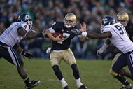 SOUTH BEND, IN - NOVEMBER 21: Jimmy Clausen #7 of the Notre Dame Fighting Irish avoids a sack by Twyon Martin #4 and Jesse Joseph #91 of the Univeristy of Connecticut Huskies at Notre Dame Stadium on November 21, 2009 in South Bend, Indiana. Connecticut defeated Notre Dame 33-30 in double overtime. (Photo by Jonathan Daniel/Getty Images)