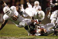 COLLEGE STATION, TX - NOVEMBER 26: Quarterback Jerrod Johnson #1 of the Texas A&M Aggies loses control of the ball as defensive tackle Kheeston Randall #91 and linebacker Roddrick Muckelroy #38 of the Texas Longhorns go for the loose ball in the first half at Kyle Field on November 26, 2009 in College Station, Texas. The officials ruled that Johnson was down before losing control of the ball. (Photo by Aaron M. Sprecher/Getty Images)