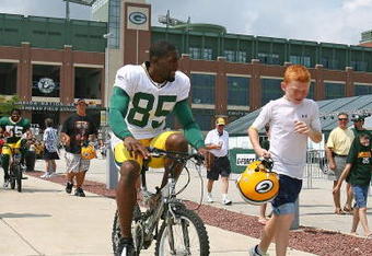 GREEN BAY, WI - AUGUST 03: Greg Jennings #85 of the Green Bay Packers rides a bike to practice as a young fan carries his helmut during summer training camp on August 3, 2009 at the Ray Nitschke Field in Green Bay, Wisconsin. (Photo by Jonathan Daniel/Getty Images)