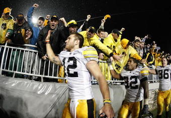 STATE COLLEGE, PA - SEPTEMBER 26:  Ricky Stanzi #12 of the Iowa Hawkeyes along with Adam Robinson #32 and Brett Morse #36 celebrate a 21-10 victory over the Penn State Nittnay Lions with Iowa fans on September 26, 2009 at Beaver Stadium in State College, Pennsylvania.  (Photo by Gregory Shamus/Getty Images)