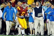 LOS ANGELES, CA - NOVEMBER 28:  Linebacker Malcolm Smith #6 of the USC Trojans runs to the end zone after intercepting a pass thrown by quarterback Kevin Prince #14 of the UCLA Bruins for a 62-yard touchdown during the first quarter of the NCAA college football game at Los Angeles Memorial Coliseum on November 28, 2009 in Los Angeles, California.  Following the action is Bruins head coach Rick Neuheisel (R).  (Photo by Kevork Djansezian/Getty Images)