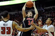 LAS VEGAS - NOVEMBER 28:  Kyle Kuric #14 of the Louisville Cardinals shoots over Tre'Von Willis #33 and Chace Stanback #22 of the UNLV Rebels during their game at the Thomas & Mack Center November 28, 2009 in Las Vegas, Nevada. The Rebels Defeated the Cardinals 76-71.  (Photo by Ethan Miller/Getty Images)