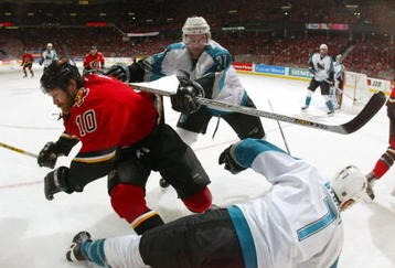 CALGARY, ALBERTA - MAY 16:  Curtis Brown #37 of the San Jose Sharks hits Dave Lowry #10 of the Calgary Flames during Game four of the 2004 NHL Western Conference Finals on May 16, 2004 at the Pengrowth Saddledome in Calgary, Alberta, Canda.  (Photo by Jeff Vinnick/Getty Images)