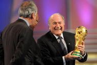 CAPE TOWN, SOUTH AFRICA - DECEMBER 04:  FIFA President Sepp Blatter (R) holds the World Cup next to South African President Jacob Zuma (C) during the Final Draw for the FIFA World Cup 2010 December 4, 2009 at the International Convention Centre in Cape Town, South Africa.  (Photo by Shaun Botterill/Getty Images)
