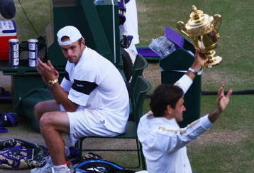 WIMBLEDON, ENGLAND - JULY 05:  Andy Roddick of USA looks despondent as Roger Federer of Switzerland celebrates with the trophy during the men's singles final match on Day Thirteen of the Wimbledon Lawn Tennis Championships at the All England Lawn Tennis and Croquet Club on July 5, 2009 in London, England. Federer won 5-7, 7-6, 7-6, 3-6, 16-14.  (Photo by Julian Finney/Getty Images)