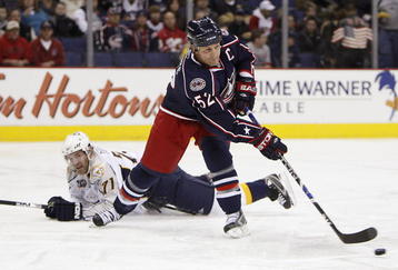 COLUMBUS - JANUARY 12:  Adam Foote #52 of the Columbus Blue Jackets controls the puck while J.P. Dumont #71 of the Nashville Predators falls on the ice after him during the NHL game at the Nationwide Arena on January 12, 2008 in Columbus, Ohio. (Photo by Gregory Shamus/Getty Images)