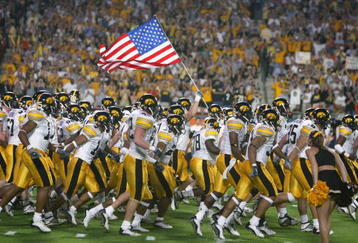 MIAMI - JANUARY 2:  The Iowa Hawkeyes take the field against USC as a team member holds the United States flag before the FedEx Orange Bowl on January 2, 2003 at Pro Player Stadium in Miami, Florida.  USC defeated Iowa 38-17.  (Photo by Eliot J. Schechter/Getty Images)