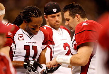 NEW ORLEANS - JANUARY 16:  Larry Fitzgerald #11 (L) and Kurt Warner #13 of the Arizona Cardinals draw out a play on Fitzgerald's hand on the sodelines against the New Orleans Saints during the NFC Divisional Playoff Game at Louisana Superdome on January 16, 2010 in New Orleans, Louisiana. The Saints won 45-14.  (Photo by Ronald Martinez/Getty Images)