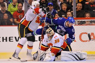 VANCOUVER, CANADA - MARCH 14: Jannik Hansen #36 of the Vancouver Canucks crashes into goalie Vesa Toskala #35 of the Calgary Flames after getting hit by Flames Jay Bouwmeester #4 during the third period of NHL action on March 14, 2010 at General Motors Place in Vancouver, British Columbia, Canada.  (Photo by Rich Lam/Getty Images)