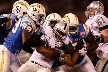 OAKLAND, CA - SEPTEMBER 14: Michael Bush #29 of the Oakland Raiders is tackled by Kevin Burnett #99 the San Diego Chargers along with other CHarger defenders on September 14, 2009 at the Oakland-Alameda County Coliseum in Oakland, California.  (Photo by E