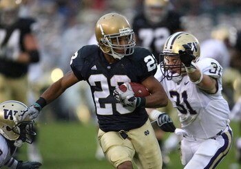 SOUTH BEND, IN - OCTOBER 03: Golden Tate #23 of the Notre Dame Fighting Irish breaks away from Quinton Richardson #28 and Cort Dennison #31 of the Washington Huskies on his way to a 67 yard touchdown on October 3, 2009 at Notre Dame Stadium in South Bend,