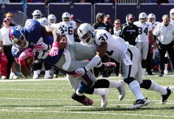 EAST RUTHERFORD, NJ - OCTOBER 11:  Brandon Jacobs #27 of the New York Giants is tackled by Tyvon Branch #33 and Hiram Eugene #31 of the Oakland Raiders on October 11, 2009 at Giants Stadium in East Rutherford, New Jersey.  (Photo by Jim McIsaac/Getty Imag
