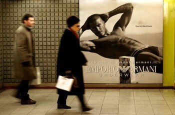 MILAN, ITALY - DECEMBER 19:  People walking in the underground pass a poster featuring David Beckham modeling underwear in the latest Emporio Armani campaign on December 19, 2008 in Milan, Italy. It is anticipated that Victoria Beckham will accompany husb