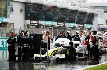 KUALA LUMPUR, MALAYSIA - APRIL 05:  Rubens Barrichello of Brazil and Brawn GP is surrounded by team mechanics in the rain during the Malaysian Formula One Grand Prix at the Sepang Circuit on April 5, 2009 in Kuala Lumpur, Malaysia.  (Photo by Paul Gilham/