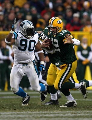 GREEN BAY, WI - NOVEMBER 30:  Aaron Rodgers #12 of the Green Bay Packers runs with the ball under pressure from Julius Peppers #90 of the Carolina Panthers at Lambeau Field on November 30, 2008 in Green Bay, Wisconsin.  (Photo by Jonathan Daniel/Getty Ima