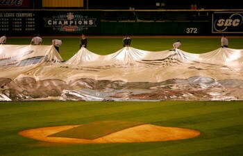 ST LOUIS - OCTOBER 26:  Rain falls as the grounds crew remove the tarps from the infield before the start of game three of the World Series between the Boston Red Sox and the St. Louis Cardinals during on October 26, 2004 at Busch Stadium in St. Louis, Mi