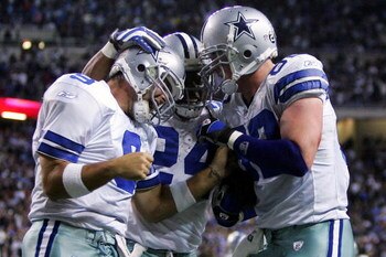 DETROIT - DECEMBER 09:  Quarterback Tony Romo #9 and Marion Barber #24 of the Dallas Cowboys congratulate teammate Jason Witten #82 (R) after he scored the winning touchdown against the Detroit Lions on December 9, 2007 at Ford Field in Detroit, Michigan.