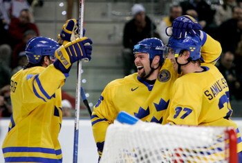 TURIN, ITALY - FEBRUARY 24:  Tomas Holmstrom #96 of Sweden celebrates with his teammates Mikael Samuelsson #37 and Henrik Zetterberg #40 after he scored the seventh goal in the third period during the semi final of the men's ice hockey match between Swede
