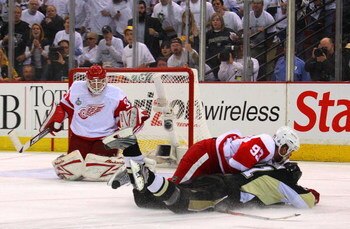 PITTSBURGH - JUNE 04:  Evgeni Malkin #71 of the Pittsburgh Penguins is knocked to the ice as he attacks against Johan Franzen #93 and goaltender Chris Osgood #30 of the Detroit Red Wings during Game Four of the 2009 NHL Stanley Cup Finals on June 4, 2009 
