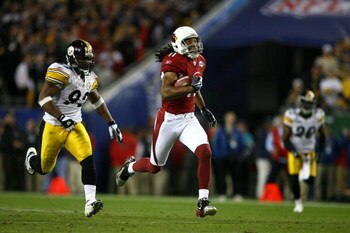 TAMPA, FL - FEBRUARY 01:  Larry Fitzgerald #11 of the Arizona Cardinals runs for yards after the catch on a 64-yard touchdown reception against James Harrison #92 and Bryant McFadden #20 of the Pittsburgh Steelers in the fourth quarter during Super Bowl X