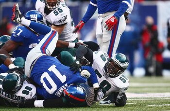 EAST RUTHERFORD, NJ -  JANUARY 11:  Eli Manning #10 of the New York Giants is tackled by Mike Patterson #98 and Trent Cole #58 of the Philadelphia Eagles during the NFC Divisional Playoff Game on January 11, 2009 at Giants Stadium in East Rutherford, New 